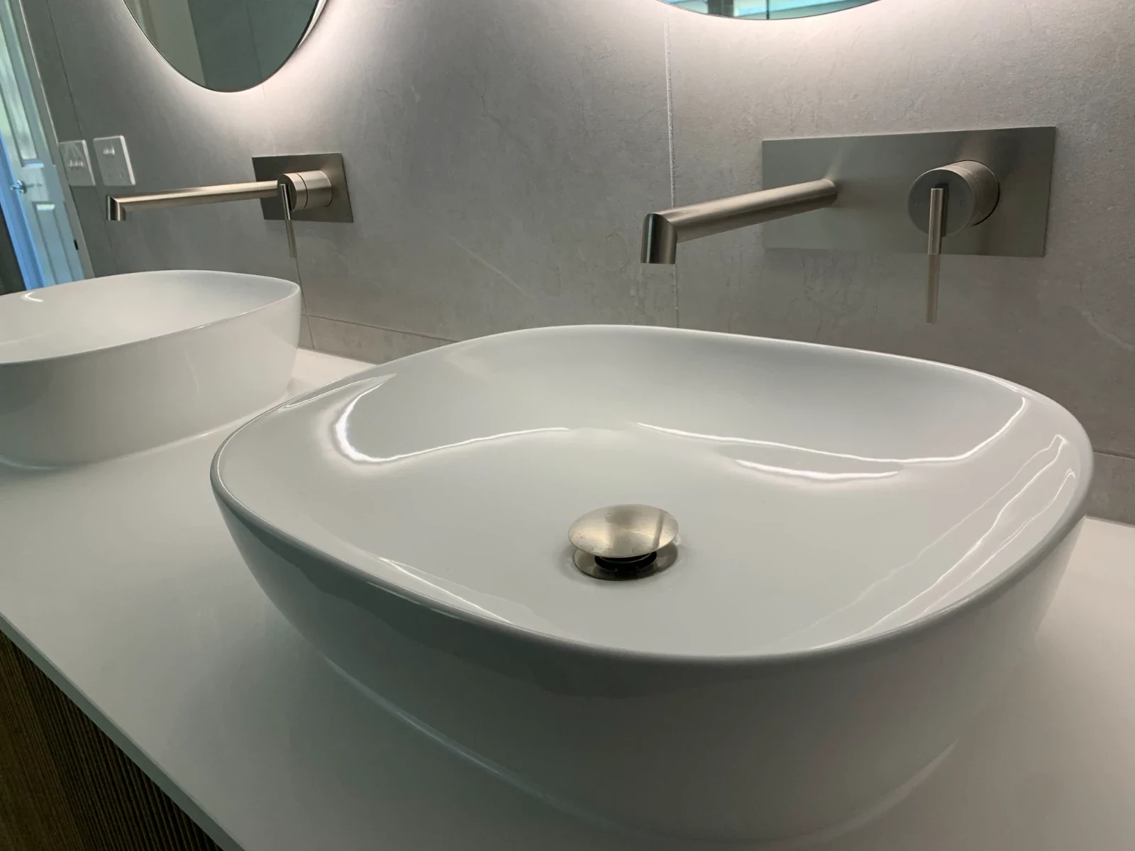 Above-counter basins with wall-mounted brushed tapware